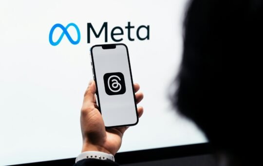 Person holding a phone displaying the Threads social media platform in front of the Meta logo as the company confirms plans to utilise content shared by its adult users in the EU (European Union) on platforms like Instagram and Facebook to train its AI models.